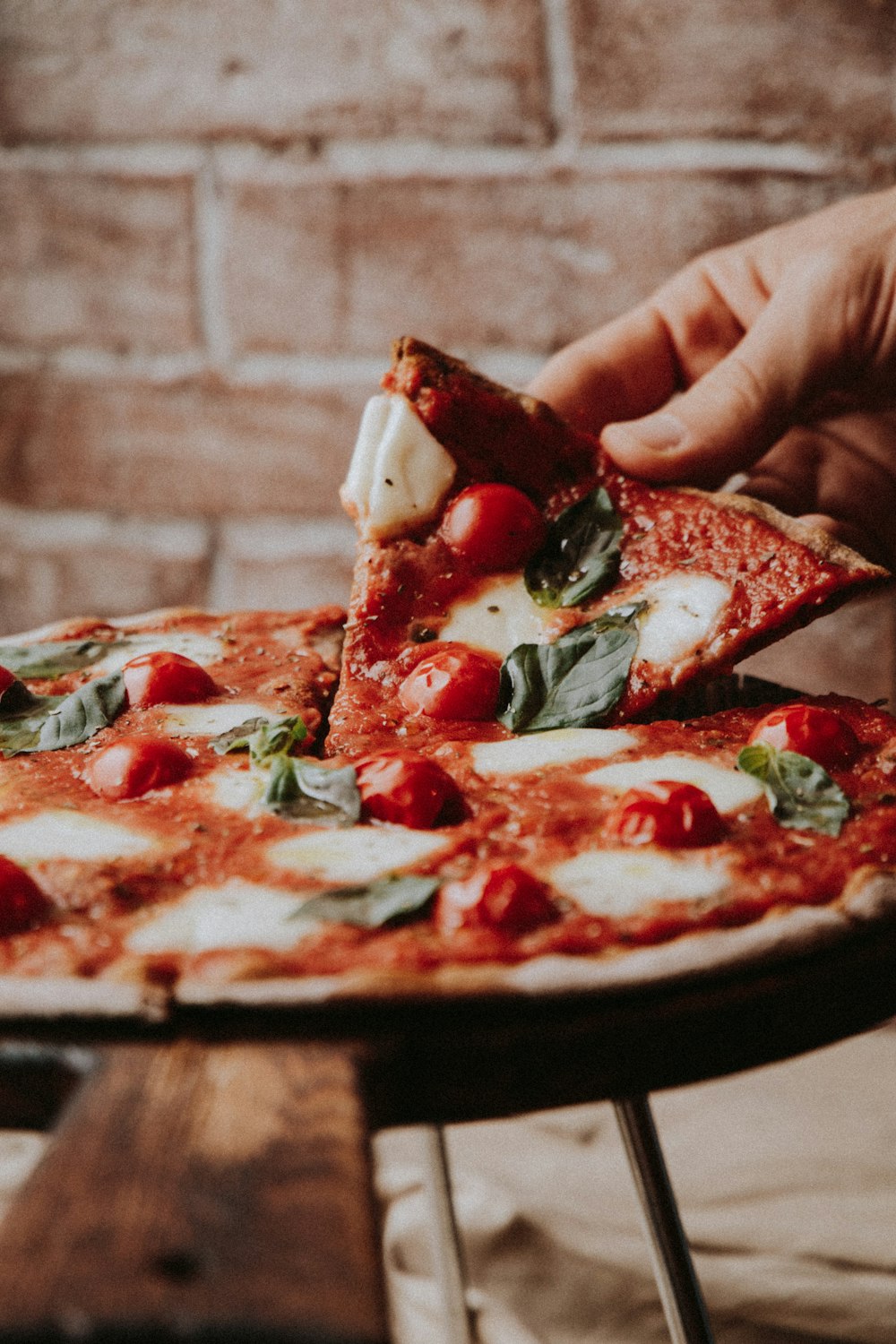 Una fetta di pizza margherita con pomodorini e basilico